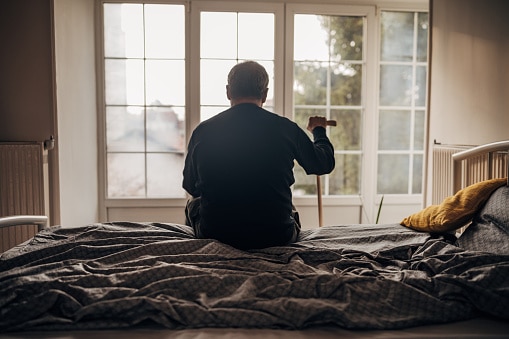 elderly man sitting on the edge of the bed with a cane nursing home abuse attorneys